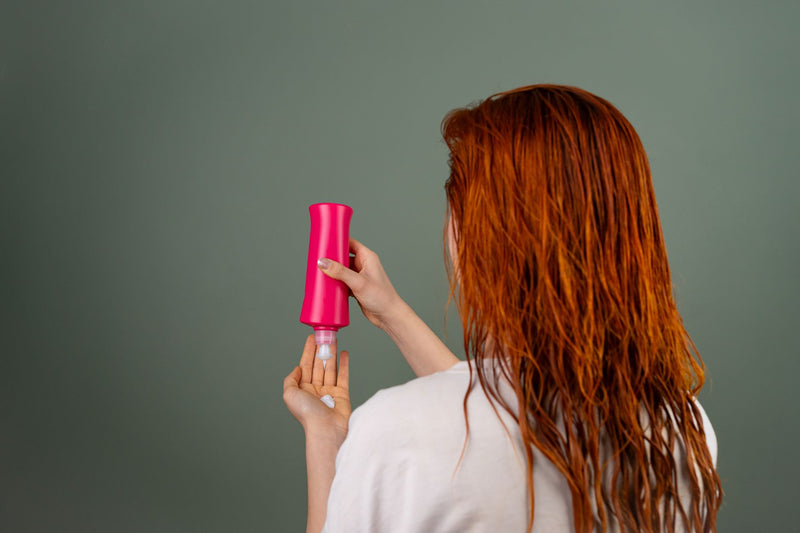 Femme appliquant un après-shampoing sur ses cheveux mouillés pendant sa routine de soin capillaire