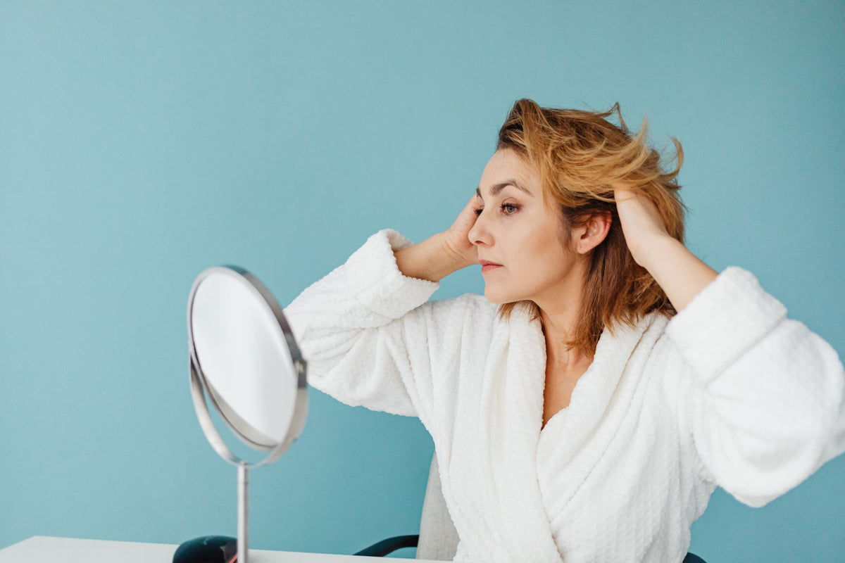 Femme prenant soin de ses cheveux devant un miroir, routine anti-casse capillaire