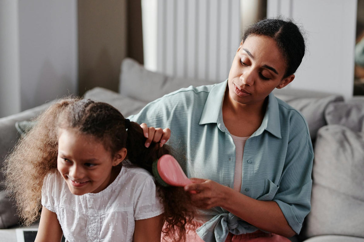 Mère brossant les cheveux bouclés de sa fille — démêler sans douleur